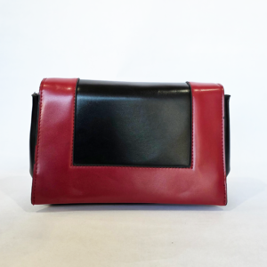 Pre-loved structured flap bag featuring a graphic two-tone red and black color-block design with black accordion sides.